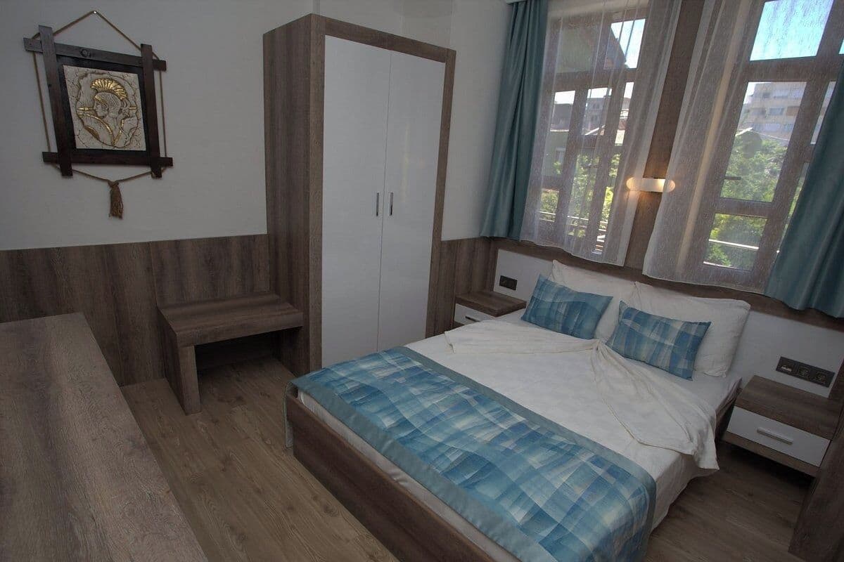 A bedroom with a bed, bedside tables, a wardrobe, and a bench.