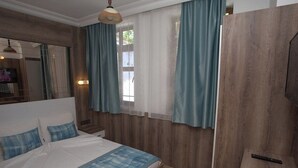 A bedroom with a bed, curtains, a wooden wardrobe, and a mirror. - Oscar Boutique Hotel (Antalya)