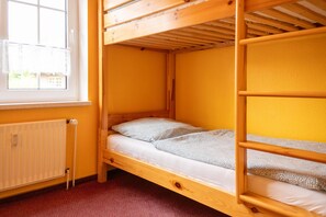 A bunk bed room with a window, radiator, and a red carpeted floor. - Cozy vacation apartment in a quiet location in Hooksiel - ideal for families and couples looking for relaxation by the North Sea. (Hooksiel)