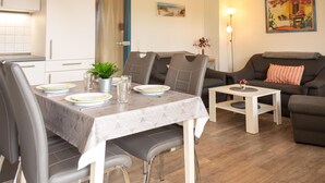 Un soggiorno moderno con zona pranzo, arredi grigi, un tavolino e un quadro appeso al muro.