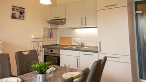 Una cucina moderna con mobili bianchi, un lavello in acciaio inossidabile e un'area pranzo con un tavolo apparecchiato per due persone.