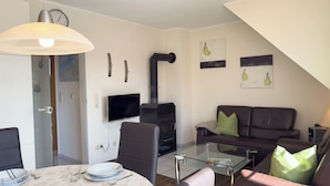 Una sala moderna con un sofá, una mesa de centro de vidrio, un televisor y una chimenea.