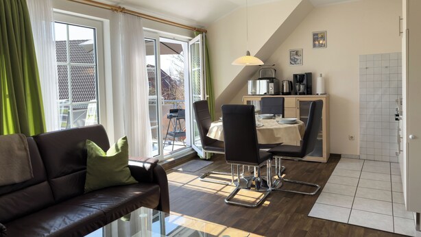 Una sala de estar moderna con un sofá, una mesa de centro de vidrio y un comedor con sillas y una mesa.