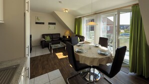 Un comedor con una mesa dispuesta para cuatro personas, un sofá y vistas al exterior.