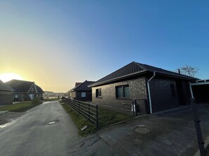 En bostadsgata med hus, en klar himmel och en solnedgång.