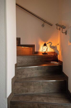 A wooden staircase with a lantern and a bird sculpture. - Modern vacation home with garden on the Wangermeer - Mee(h)rzeit offers comfort, style and relaxation for the whole family, including four-legged friends. (Wangerland)