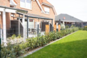 A residential building with a covered outdoor area, a brick facade, and a well-maintained lawn. - Modern vacation home with garden on the Wangermeer - Mee(h)rzeit offers comfort, style and relaxation for the whole family, including four-legged friends. (Wangerland)