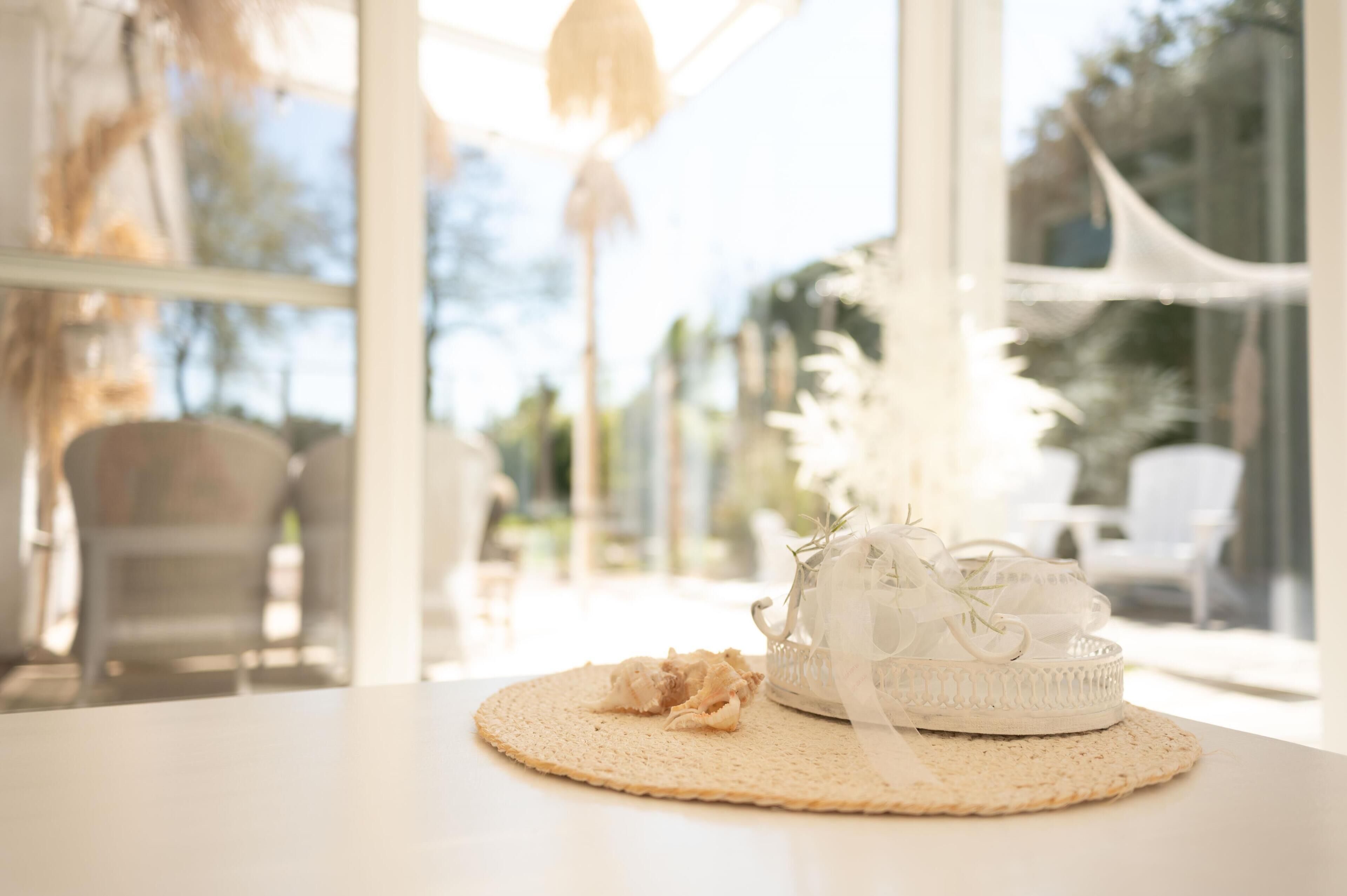 Un tavolo rotondo con un sottopiattino intrecciato, un oggetto decorativo bianco e un piccolo boccone di cibo.