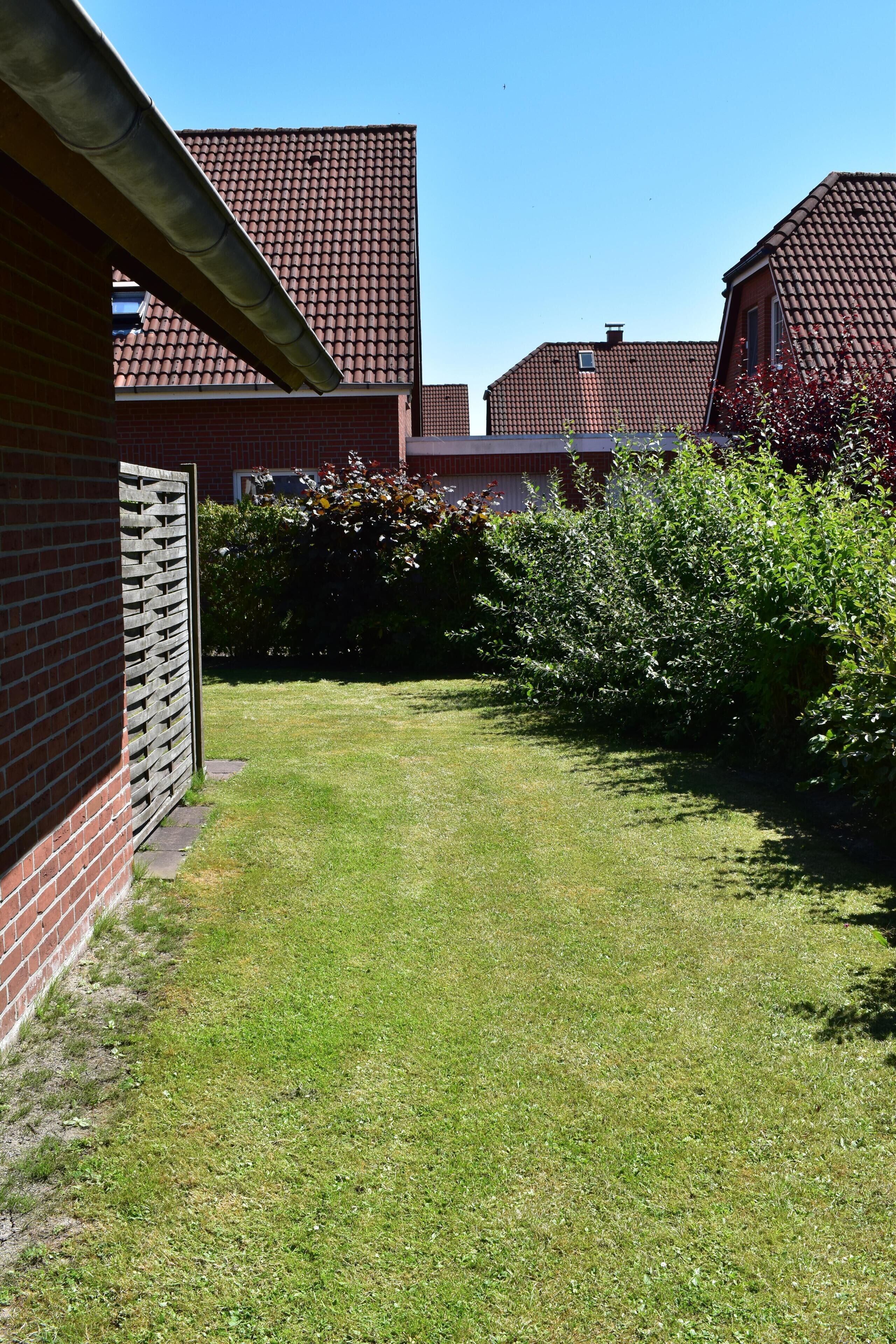 A residential area with a well-maintained lawn, brick buildings, and a wooden fence.