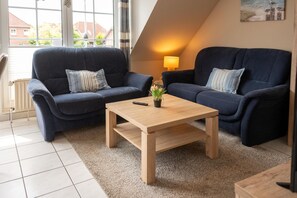 Ein gemütliches Wohnzimmer mit zwei dunkelblauen Sofas, einem Holztisch und einer Lampe.