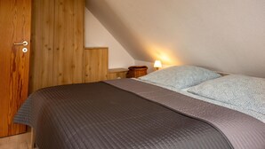 Un dormitorio con cama, un armario de madera y una mesita de noche con lámpara.