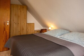 Ein Schlafzimmer mit einem Bett, einem Holzschrank und einem Nachttisch mit Lampe.
