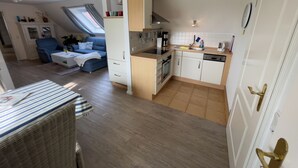 Una cocina compacta con comedor, sofá y ventana con cortinas.