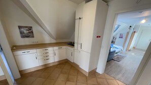 Una cocina con armarios blancos, encimera de madera y suelo de baldosas.