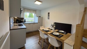 Een compacte keuken met een eethoek, een raam met uitzicht en een kleine koelkast.