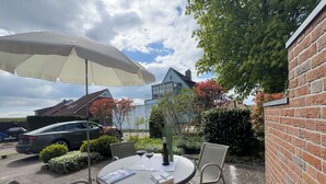 Een terras met een tafel, stoelen en een parasol.