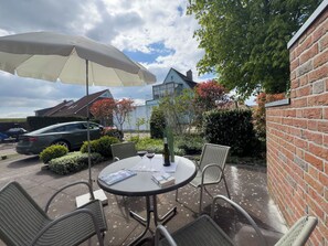 A patio with a table, chairs, and an umbrella.