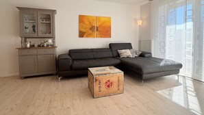 Een moderne woonkamer met een grijze bank, een houten kast en een schilderij aan de muur.