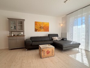 A modern living room with a grey sofa, a wooden cabinet, and a painting on the wall.
