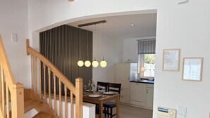 Een moderne keuken met een eethoek, houten trap en hanglampen.