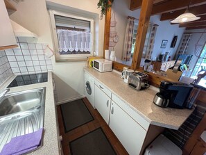 A compact kitchen with a sink, microwave, toaster, and coffee maker. - The charming Tillmann vacation home offers modern furnishings, a cozy wooden ambience and a sunny southwest-facing terrace - just a few minutes' walk from the dyke. (Hooksiel)