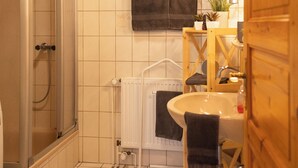 A bathroom with a shower, a sink, and a radiator. - The spacious Tillmann vacation home offers a cozy wooden ambience, modern comfort and an inviting garden - just a few minutes' walk from the dyke. (Hooksiel)