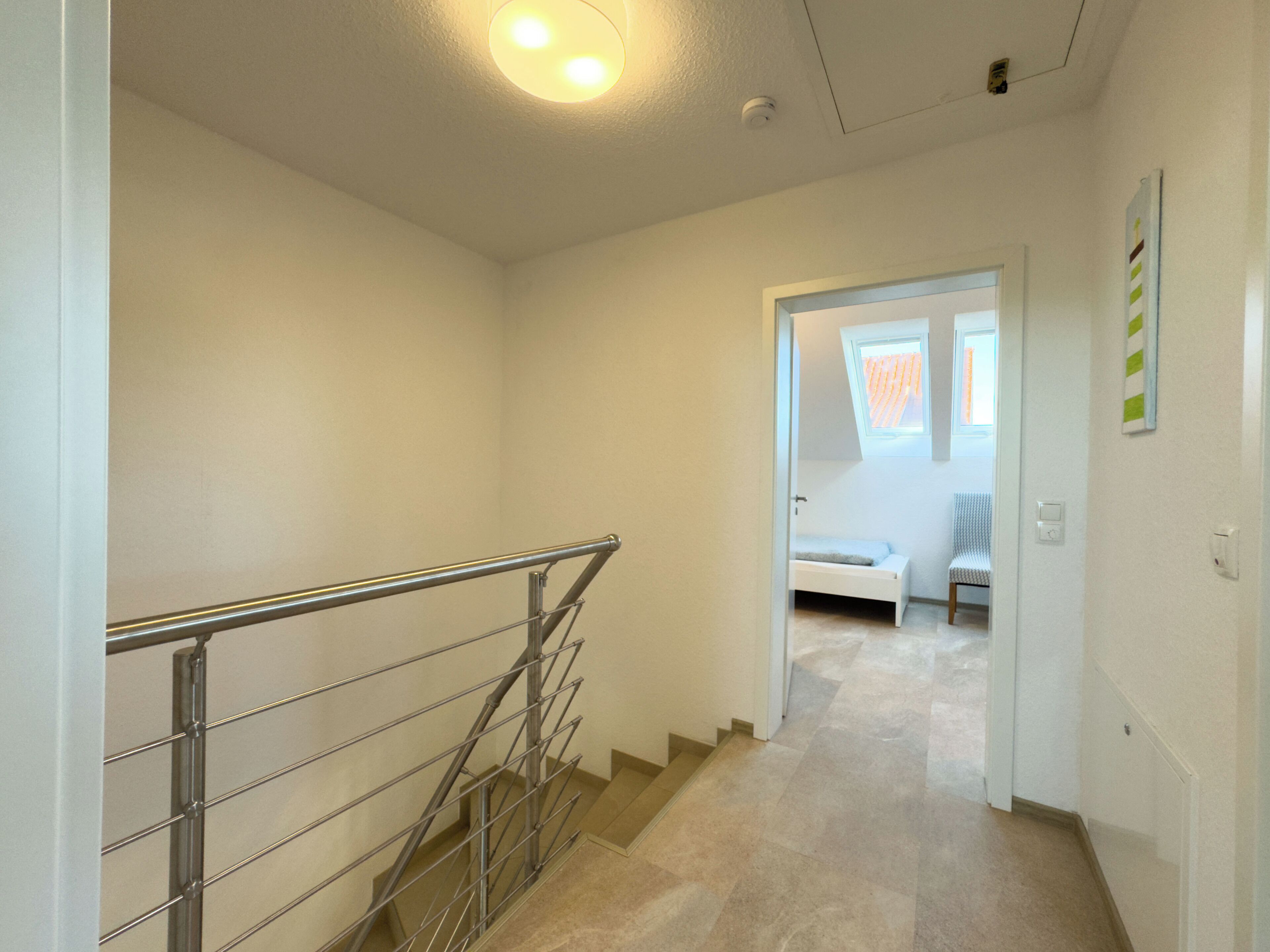 A staircase with metal railings leading to a bedroom with a bed and a window.
