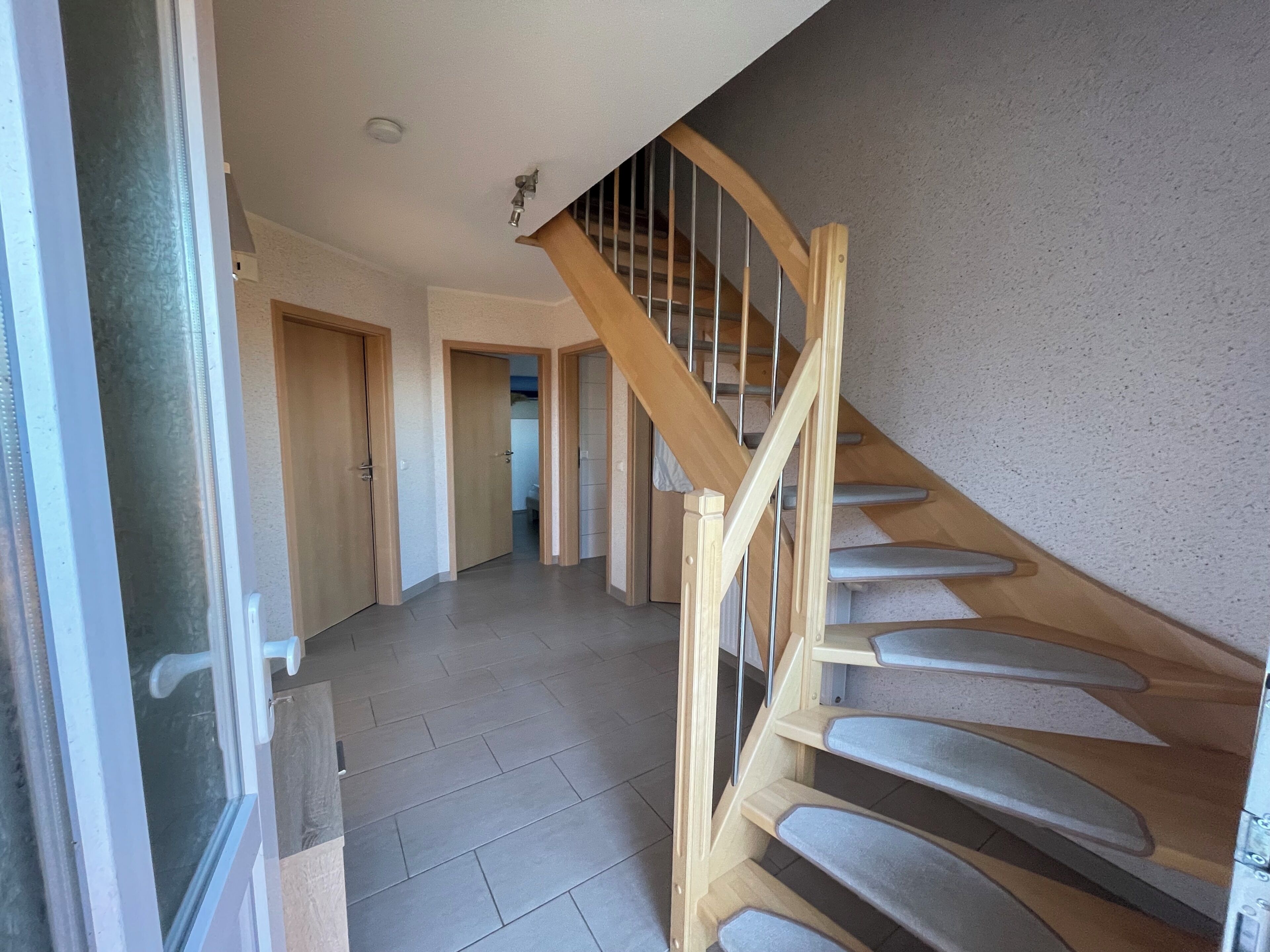 Eine Treppe mit Holzgeländern und Fliesenboden, die zu einer oberen Ebene führt.