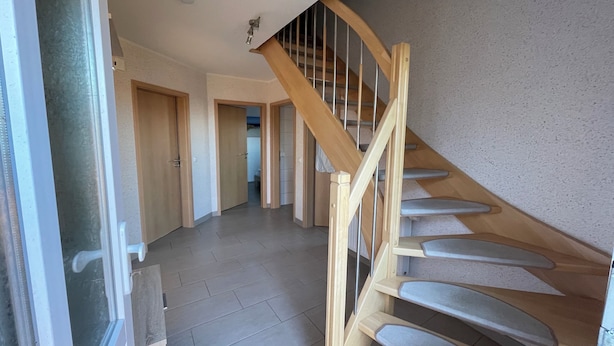 A staircase with wooden railings and a tiled floor leading to an upper level. - The Wangernest vacation home offers family-friendly comfort in the immediate vicinity of the Wangermeer and its own private beach. (Wangerland)