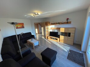 Ein Wohnzimmer mit Sofa, Couchtisch, Fernseher und Holzschränken.