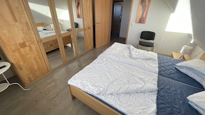 A bedroom with a bed, wooden wardrobe, and a chair. - The Wangernest vacation home offers family-friendly comfort in the immediate vicinity of the Wangermeer and its own private beach. (Wangerland)