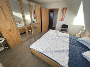 Ein Schlafzimmer mit einem Bett, einem Schrank aus Holz und einem Sessel.
