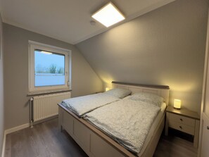 Makuuhuone, jossa on sänky, yöpöytä, ikkuna ja kattovalaisin.