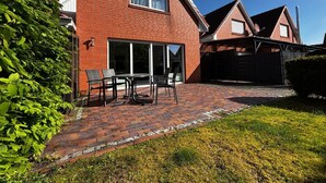 Een rode bakstenen woning met terras, een schuifpui en een omheinde achtertuin.