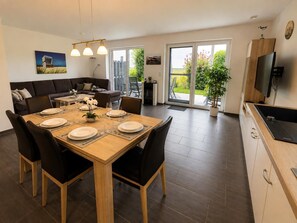 A modern dining area with a wooden table set for four, surrounded by black chairs. - Comfortable vacation home "Austernfischer" in Wangerland near the North Sea with sauna, 3 bedrooms for up to 5 guests - dogs welcome. (Wangerland)
