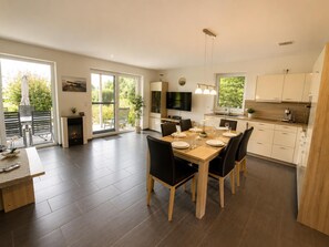 A modern kitchen with a dining area, large windows, and a fireplace. - Comfortable vacation home "Austernfischer" in Wangerland near the North Sea with sauna, 3 bedrooms for up to 5 guests - dogs welcome. (Wangerland)