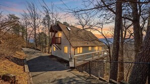 Una casa con techo inclinado, un balcón y vista a los árboles circundantes.