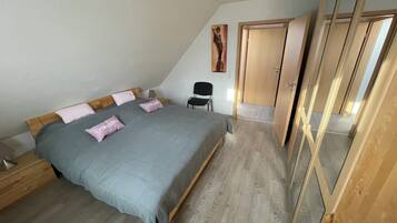 Un dormitorio con una cama, una silla, un armario y un cuadro en la pared.