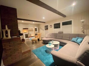 A living room with a sectional sofa, a coffee table, a fireplace, and a dining area with chairs.