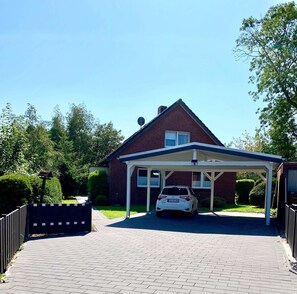 A house with a covered driveway and a parked car.