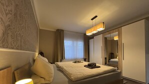 Habitació d'hotel amb llit, una làmpada de nit, finestra amb cortines i un mirall.