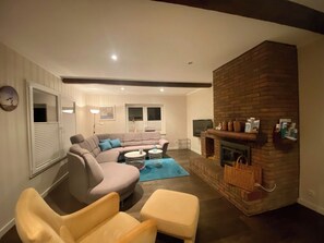 A living room with a brick fireplace, a sofa, a coffee table, and a TV.