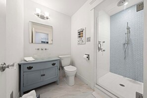 Een badkamer met toilet, wastafel met spiegel en douche.