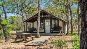 Eine Hütte mit Veranda, Picknicktisch und Bänken.
