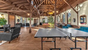 Ein großzügiger Innenbereich mit Tischtennisplatte, Sitzgelegenheiten und Holzbalken.