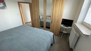 Una camera da letto con un letto, un armadio, una scrivania e una televisione.