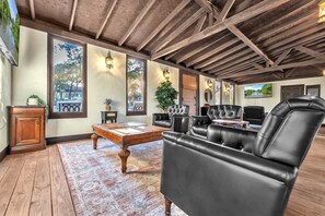 A spacious room with a wooden ceiling, large windows, and leather furniture. - The Vineyards: Cabin 2 - Private Hot Tub & Shared Pool (Fredericksburg)