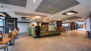 A spacious café area with a counter, seating, and a view of the outside. - Studio em frente a UFSC e HU - 319A (Florianópolis)
