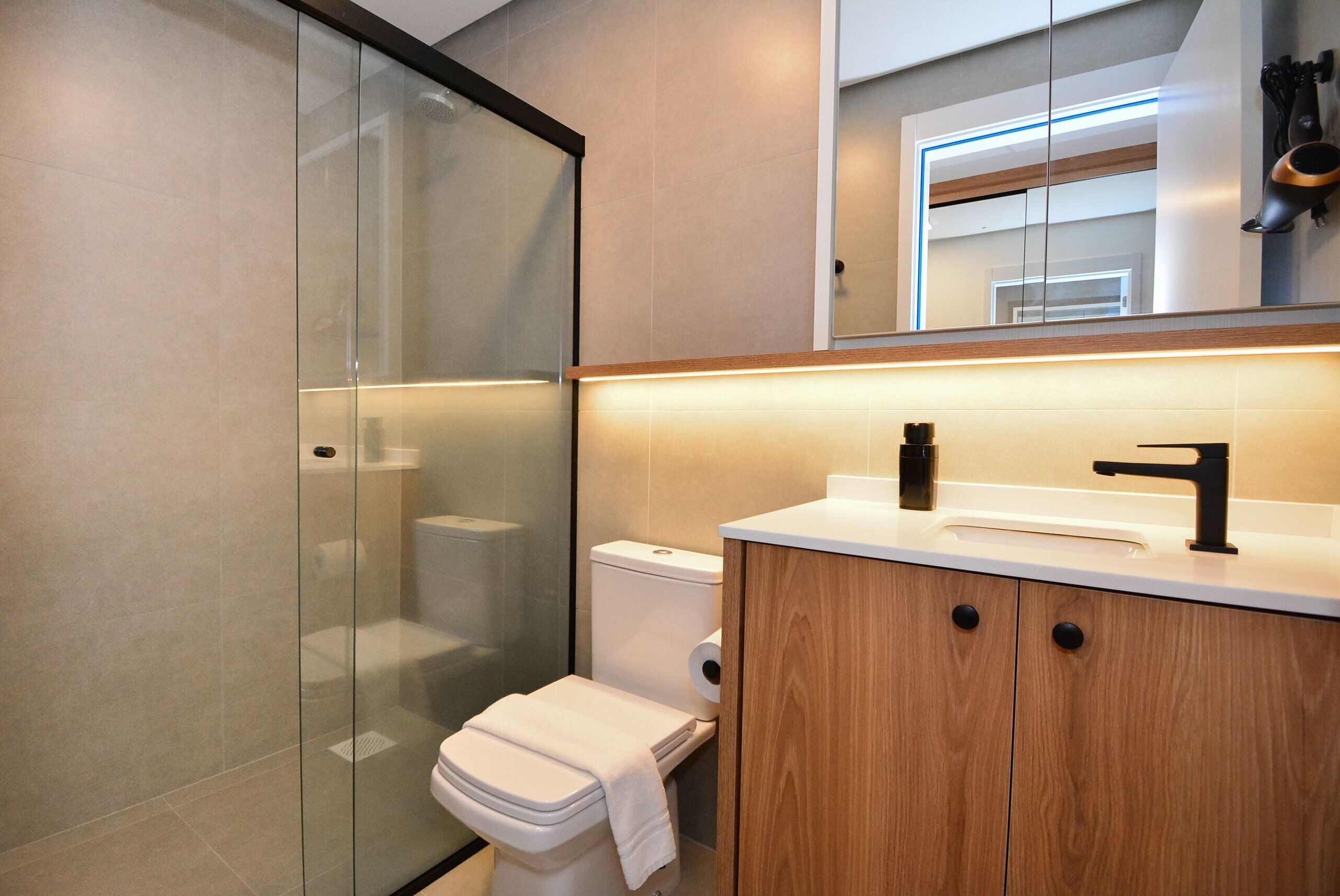 Ein modernes Badezimmer mit einer Duschkabine aus Glas, einer Toilette und Holzschränken.