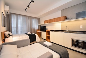 A modern hotel room with two beds, a kitchenette, and a large window with curtains. - Studio em frente a UFSC e HU - 319A (Florianópolis)